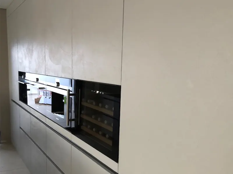 Küchenzeile mit grifflosen Fronten und Wand in heller Mikrozement-Optik
